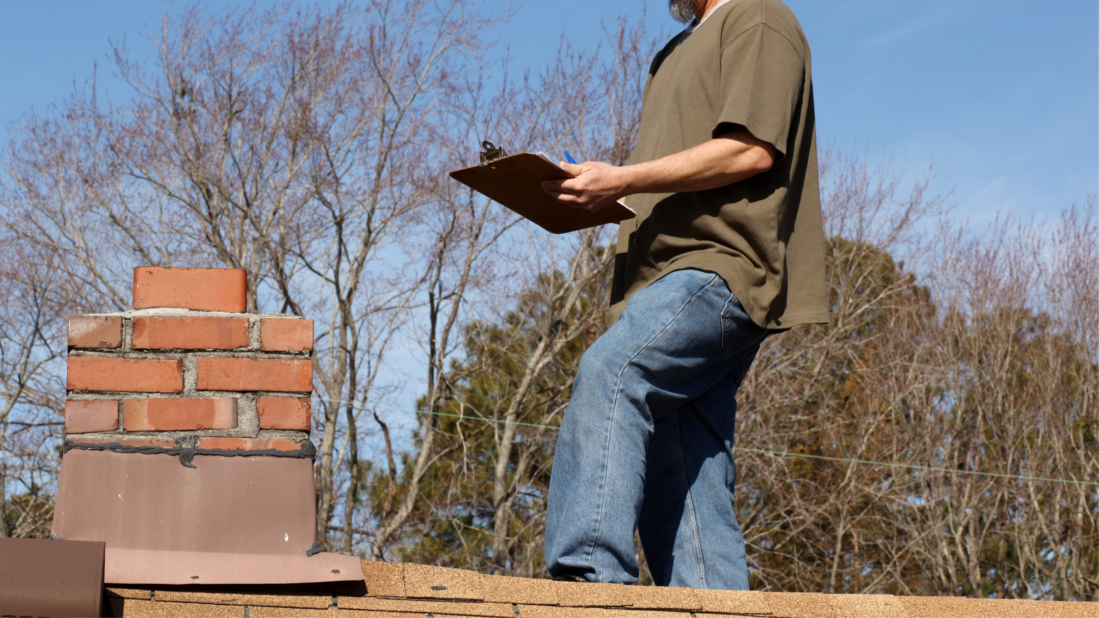 Technician inspecting a chimney cap from the roof